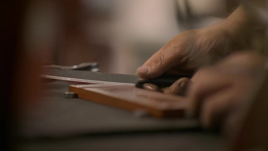 Closeup of a persons hands sharpening a knife on a file