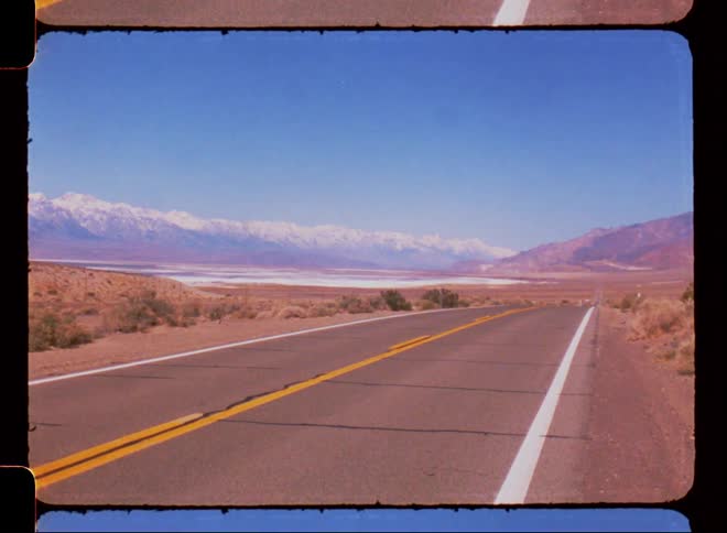 Paved street in a place with desert vegetation with mountains on the horizon with snow