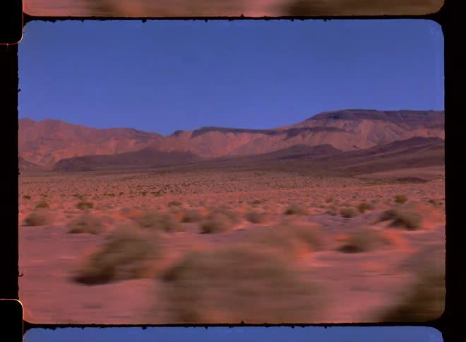 Desert landscape hillside shrubbery during the day scene from moving vehicle