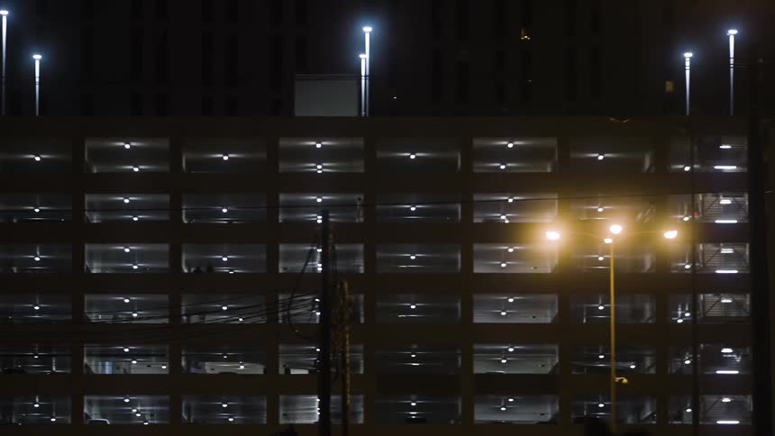 A large concrete parking structure is illuminated at nighttime