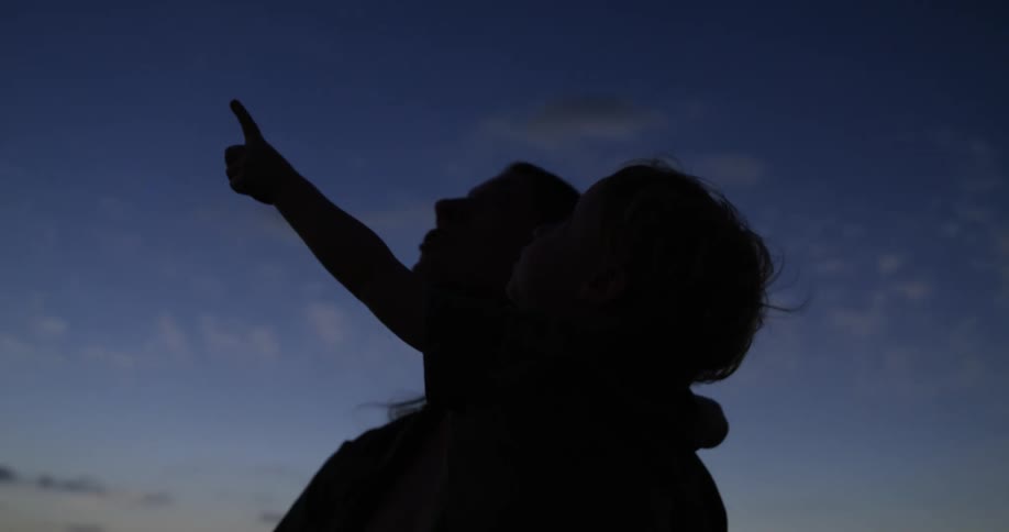 A mother and child points at a solar eclipse