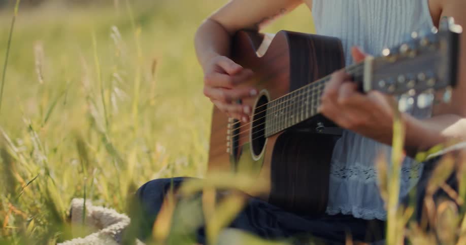 A person playing acoustic guitar in a park