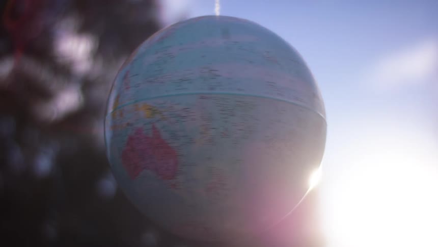 Globe map rotates outdoors sun flare