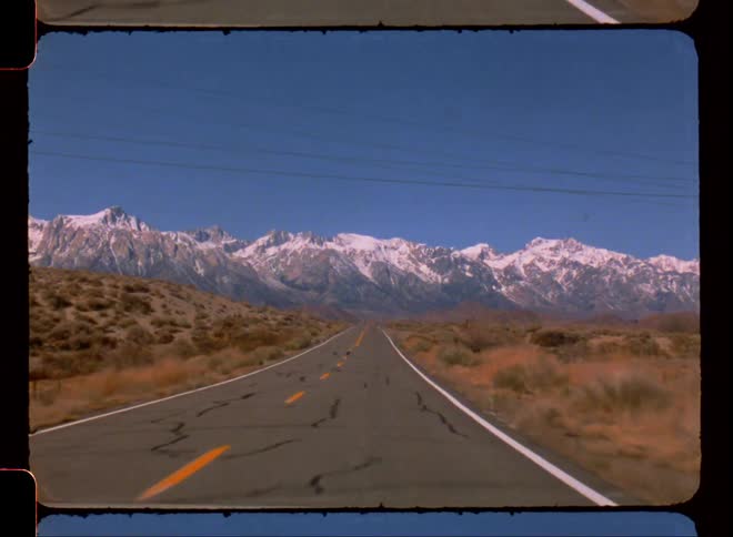 A desert highway in a remote area with a mountain range in the foreground