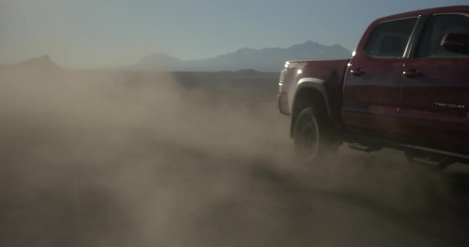 A truck generates clouds of dust by speeding down a dirt road