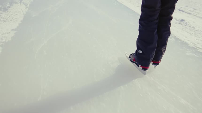 Camera closely follows a person ice skating over a frozen lake