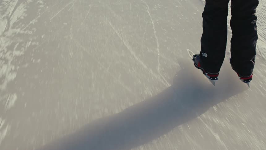 Slow motion shot of a person ice skating on a large frozen lake