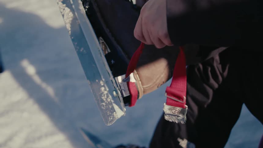 A person straps ice skates to a boot as she prepares for wild skating