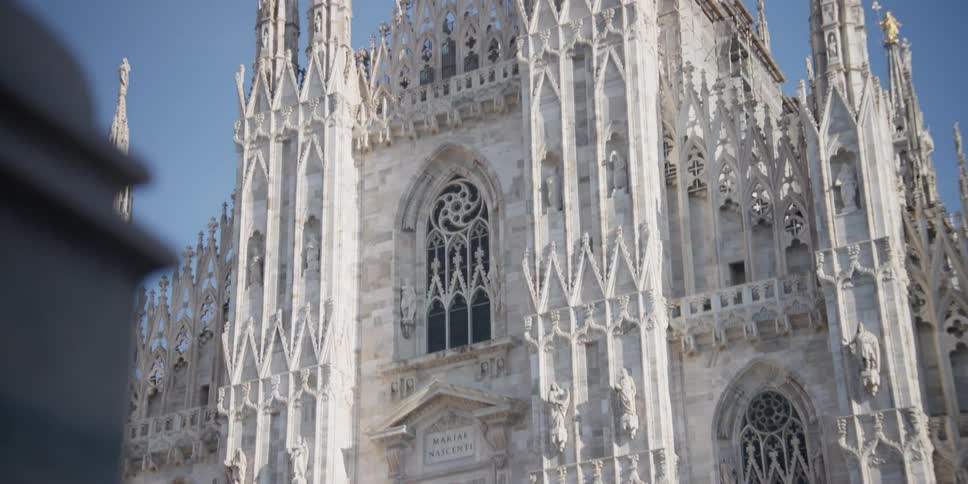 Exterior architecture facade of Cathedral Duomo di Milano in Milan, Italy on a cloudless blue sky day