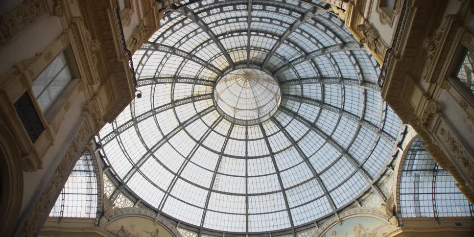 People walk under a large glass dome of the Galleria Vittorio Emanuele II shopping mall in Milan, Italy
