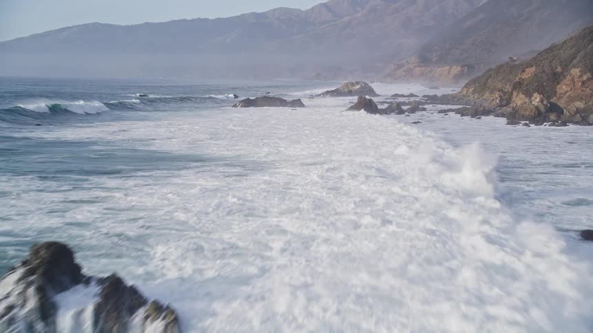 Strong waves hitting a coastal mountain range