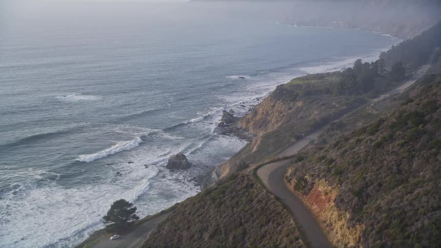 Winding road that runs parallel to a rocky coastline and alongside the sea