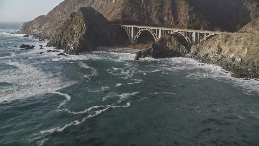 A bridge crosses mountains on a coast