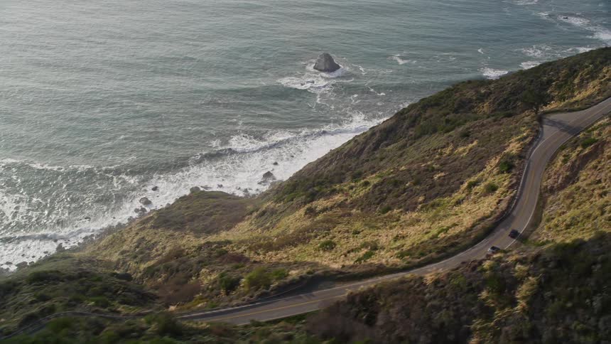 Aerial landscape of a road amidst mountains and close to the sea