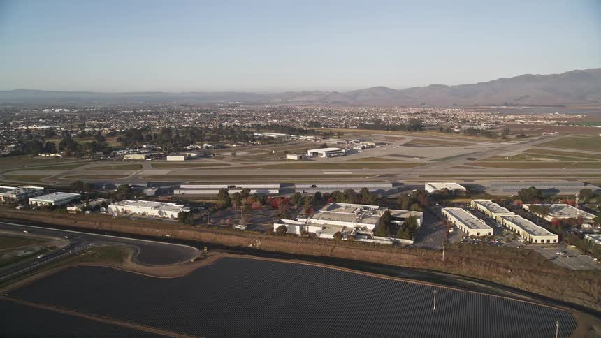 Aerial panorama of agricultural fields and an aviation landing strip with mountains on the horizon