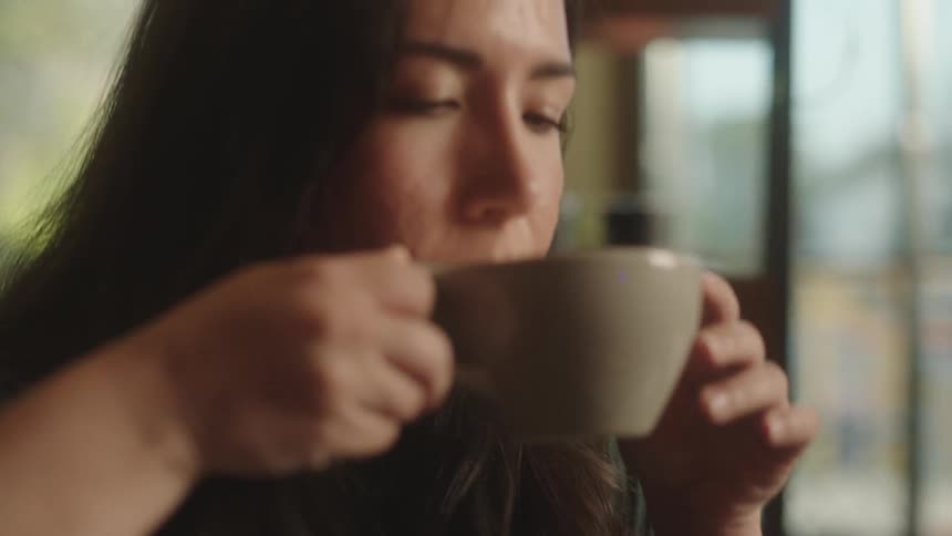 A woman is drinking coffee at a coffeeshop