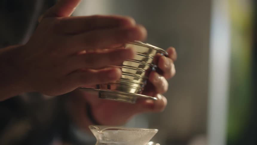 Barista taps filled top of pour over coffee maker