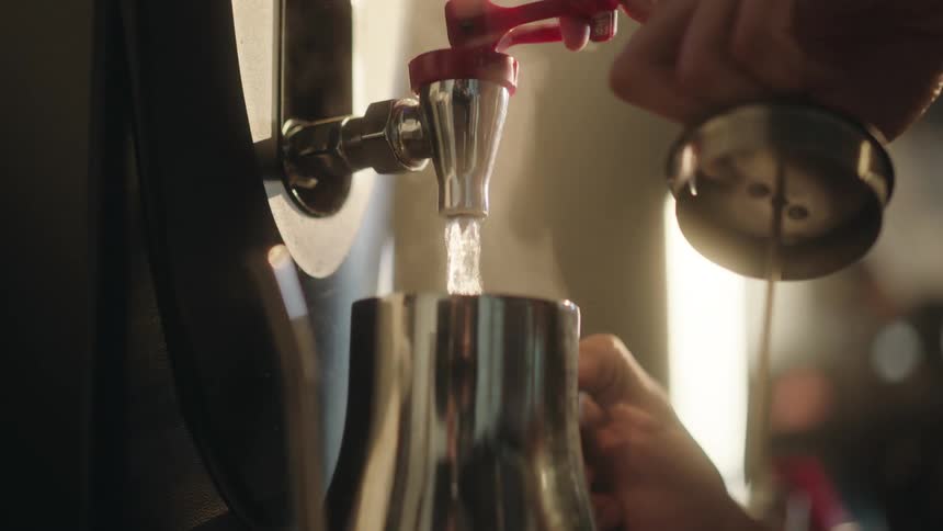 Hands of a person holding a kettle and pouring hot water into it