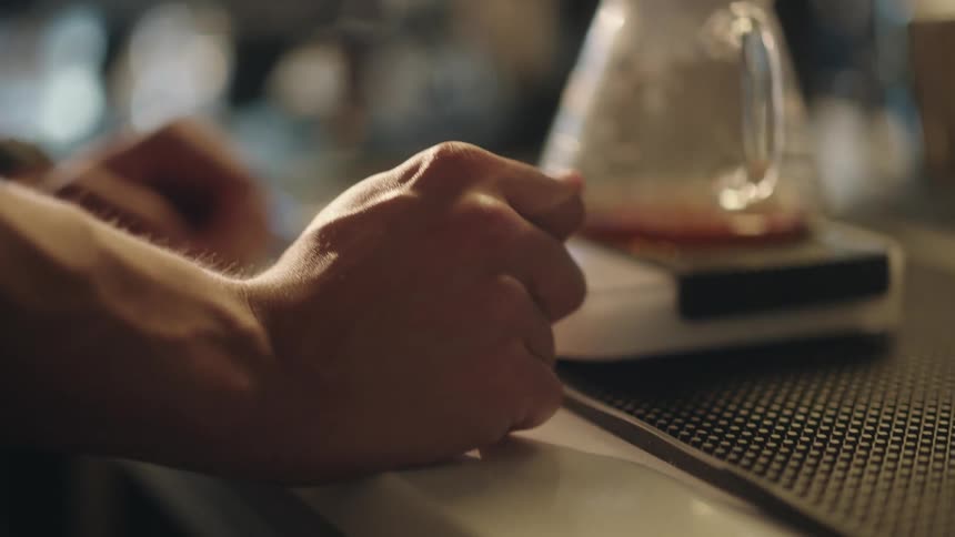 Hands of a man waiting for the coffee to be filtered