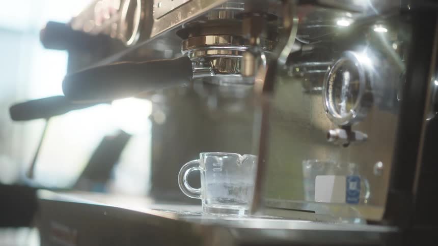 Mans hand placing a cup into an espresso machine