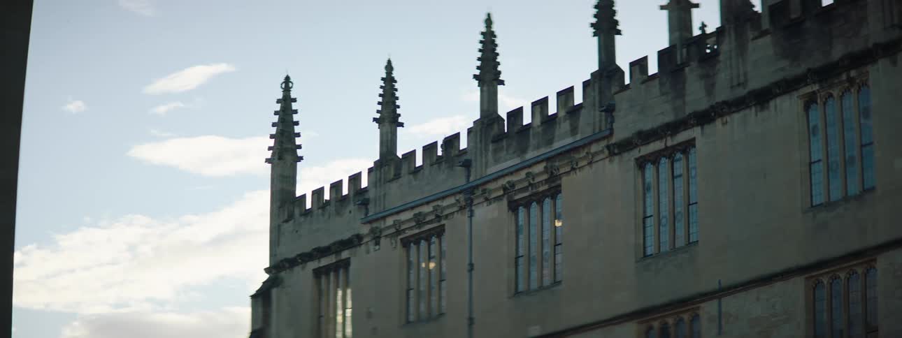 Clouds hover in sky near a building with pointed decorated columns on the roof