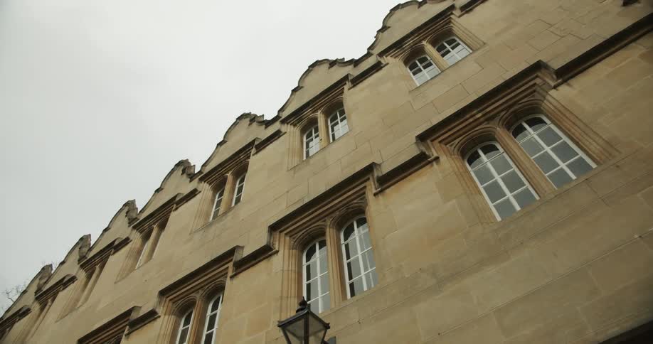 Long downspout runs down front of a building with arched windows on an overcast day