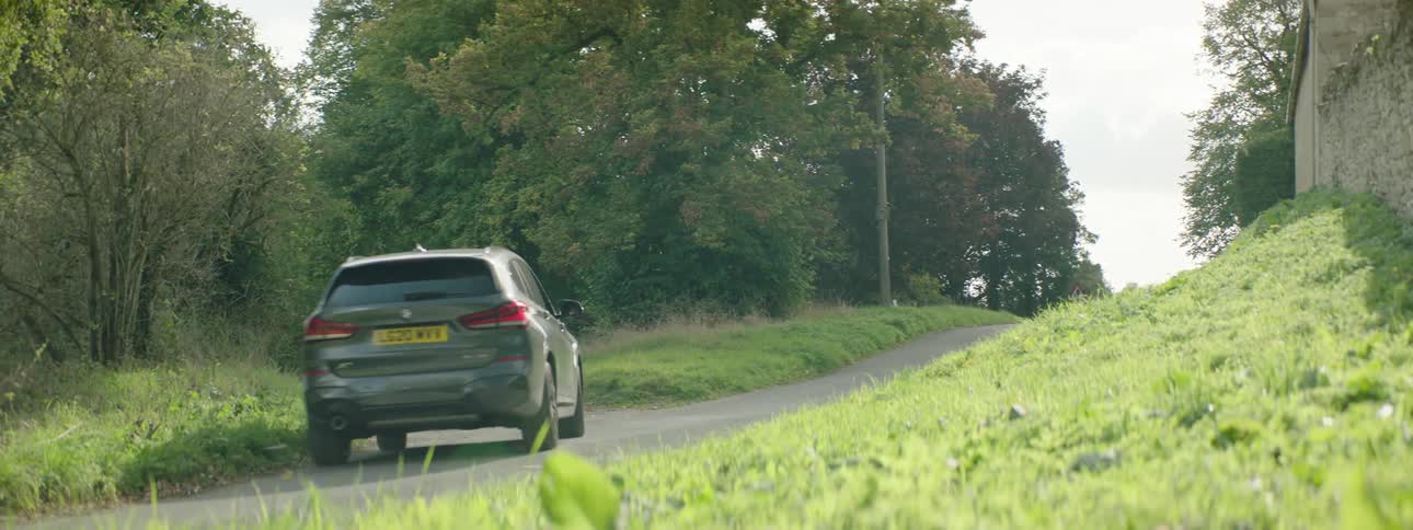 Gray suv car entering a narrow street with trees around during the day