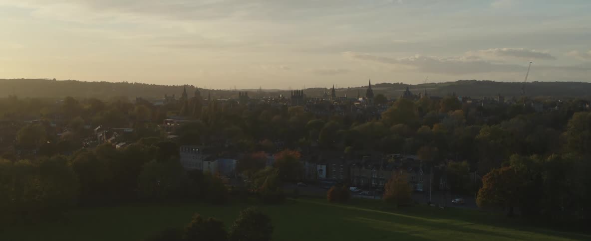 Aerial panorama of an urban city with vast greenery of spring trees and mountain ranges on the horizon