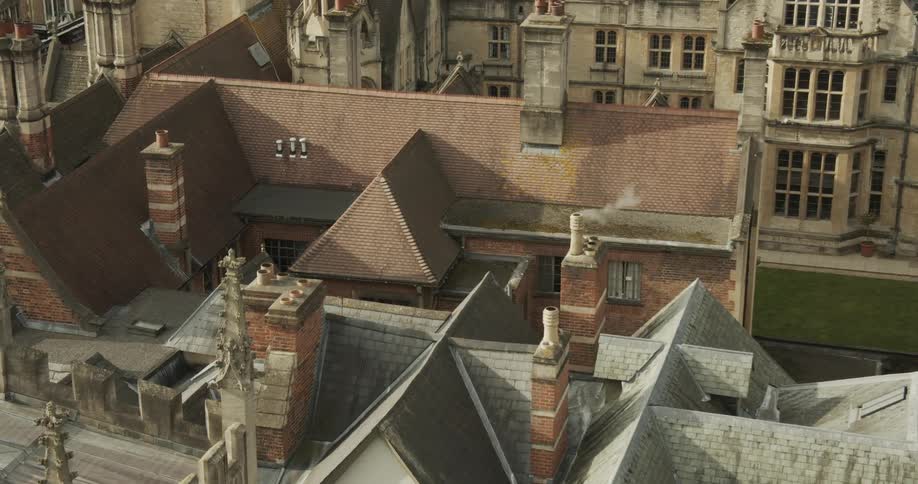 Some roofs of small houses with chimneys and one of them is releasing smoke