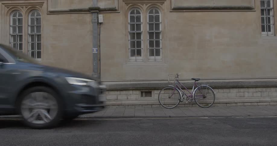 Vehicles drive past a bicycle parked in the sidewalk