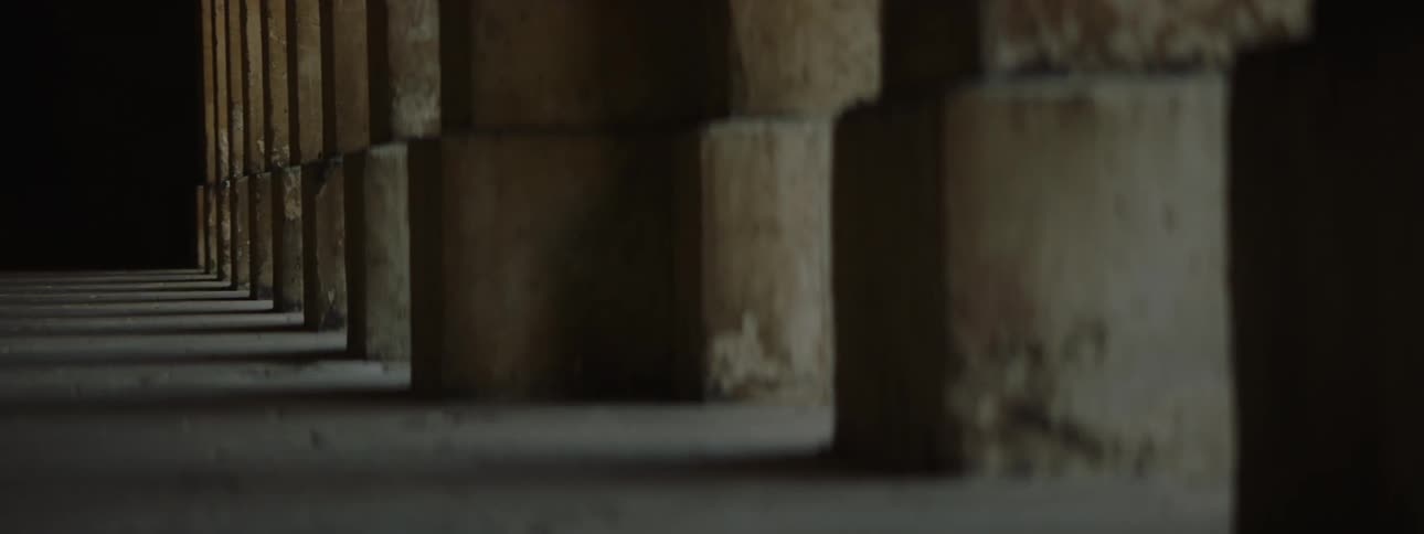 A dimly lit corridor with a series of columns on one side