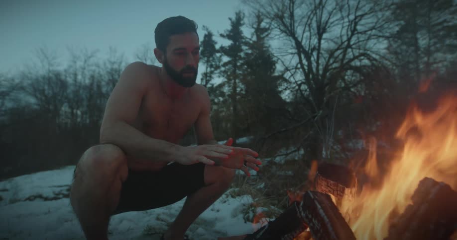 A man is warming himself by the campfire