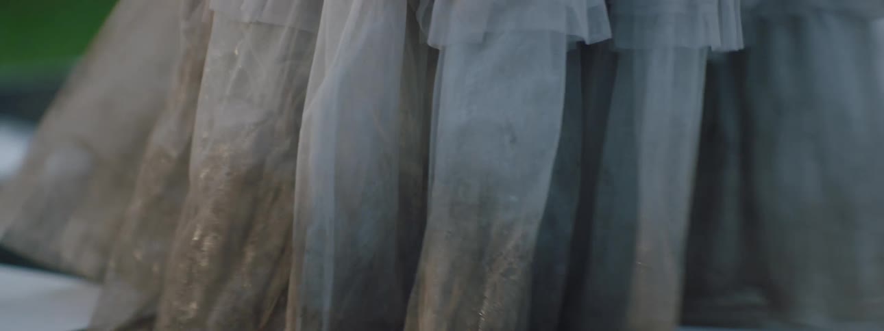 Legs of a woman wearing a long dress with a dirty hem while walking outdoors