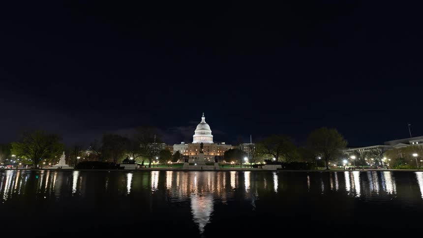 A domeshaped building in front of a lake that reflects the entire environment from above at night