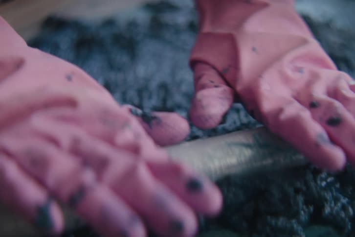 A worker rolls an object over black goo