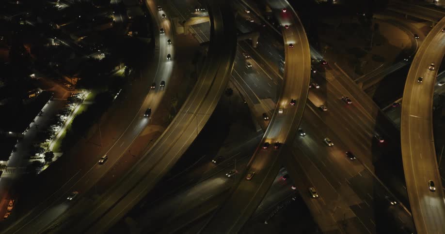 Aerial panorama of intersections and overpasses in an urban city at night with vehicle traffic