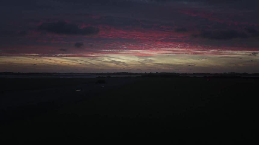 Silhouette of a landscape of grasslands and mountains with a dark purple and reddish dawn sky