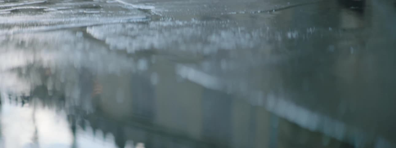 A building reflected in a puddle on pavement