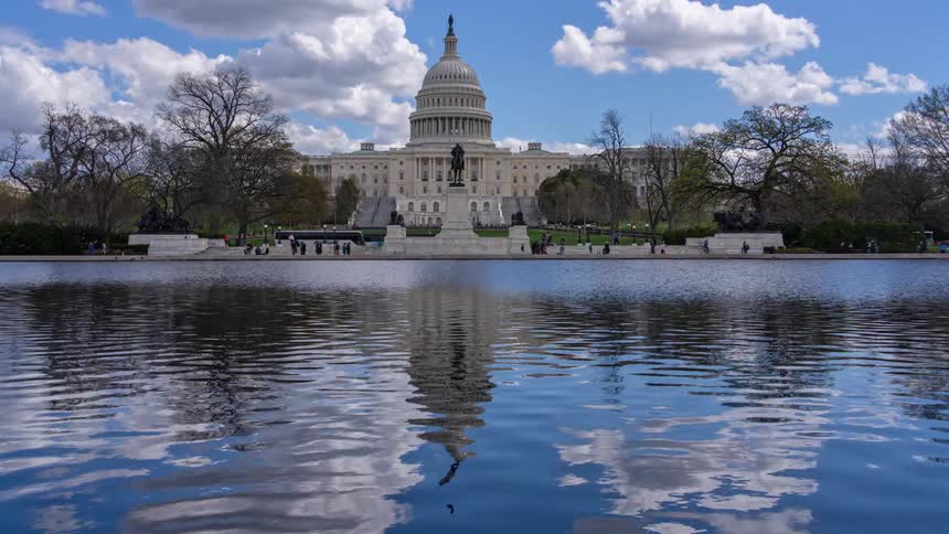Panorama of the washington capitol with pedestrian and vehicle traffic in front of a lake during the day