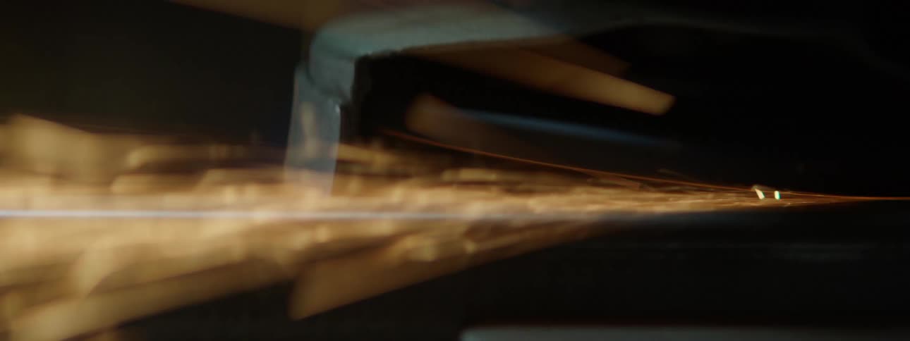Closeup of a metal sheet being shaped and sparks coming out