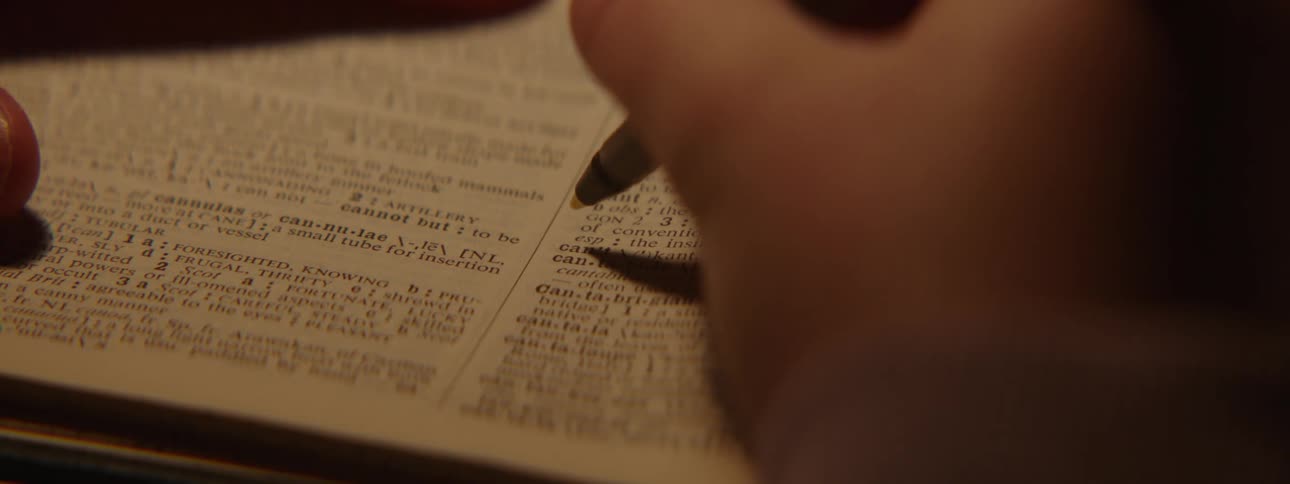 Extreme closeup of a persons hand holding a pen and reading a written page