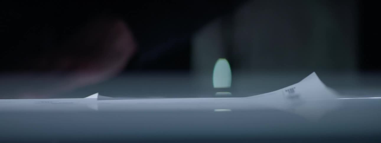 Hands of a man with a pen writing on papers on a table in a dark environment with flashing lights