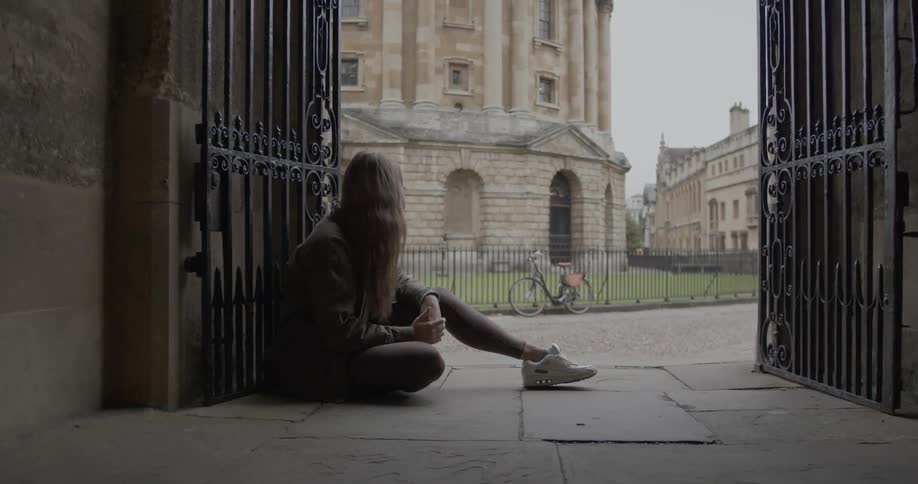 Woman sitting at a gate in front of a square