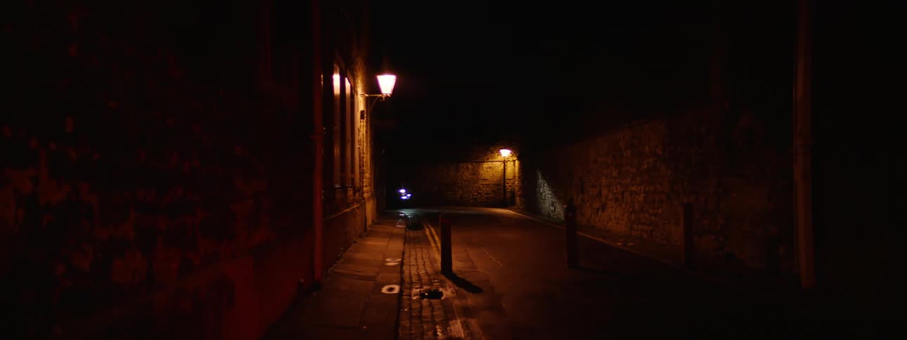 Two motorcycles driving down a narrow street