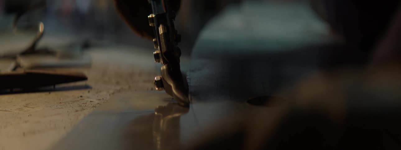 Closeup of a persons hand with gloves using cutting and pressing pliers on a sheet of metal