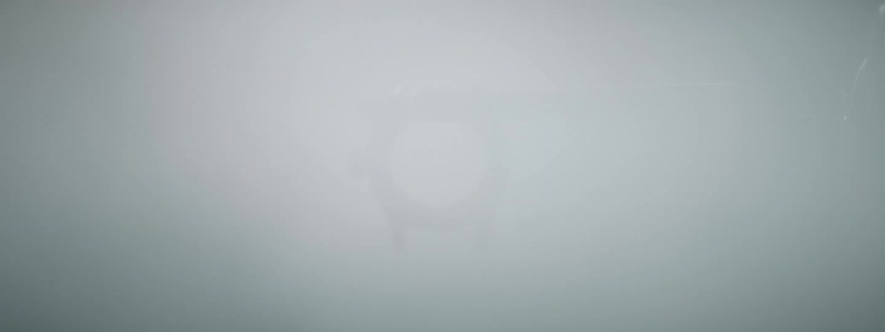 Extreme closeup of a round metal object being held by tweezers and a jet of water passing by