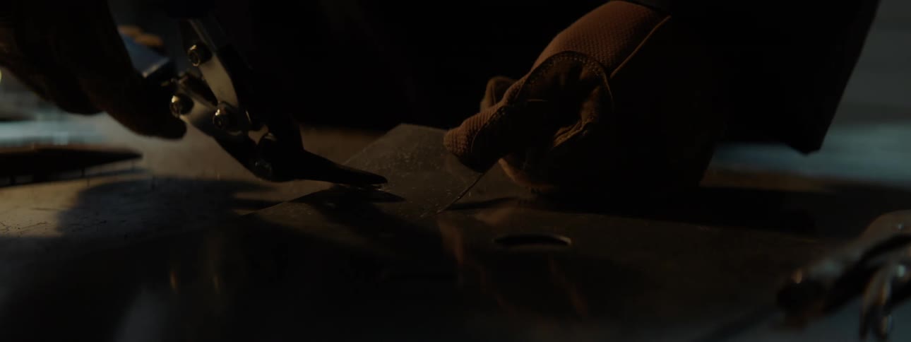Hands of a man cutting a piece of metal with cutting pliers