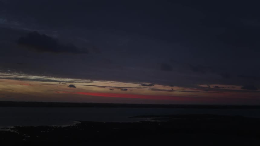 Aerial landscape of a purple and reddish sky at dawn over land and sea