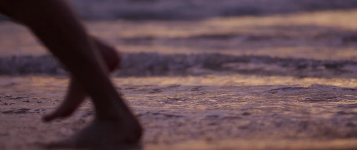 A person walks through the water on the shore