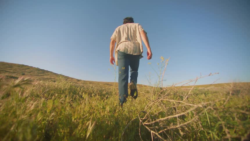 A man is walking through through the tall grass